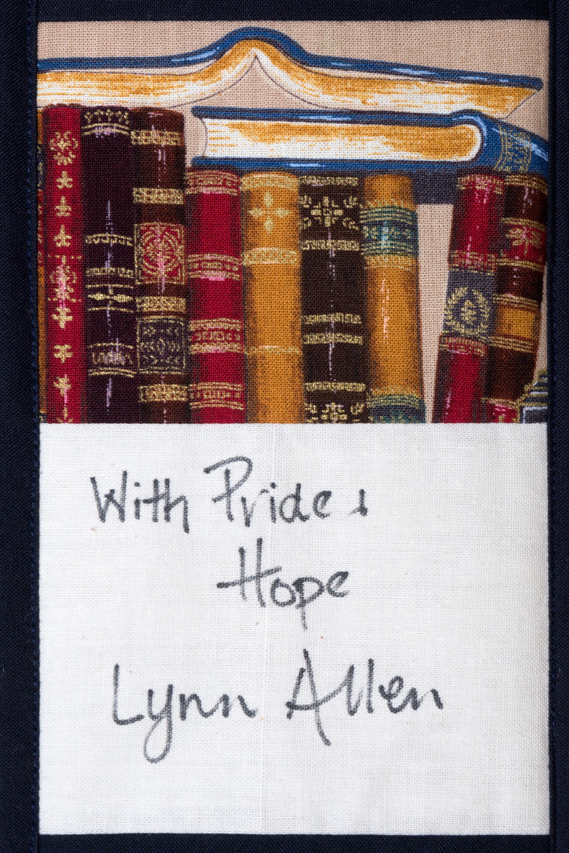 Handwritten note reading “With Pride & Hope, Lynn Allen” below colorful fabric bookshelves