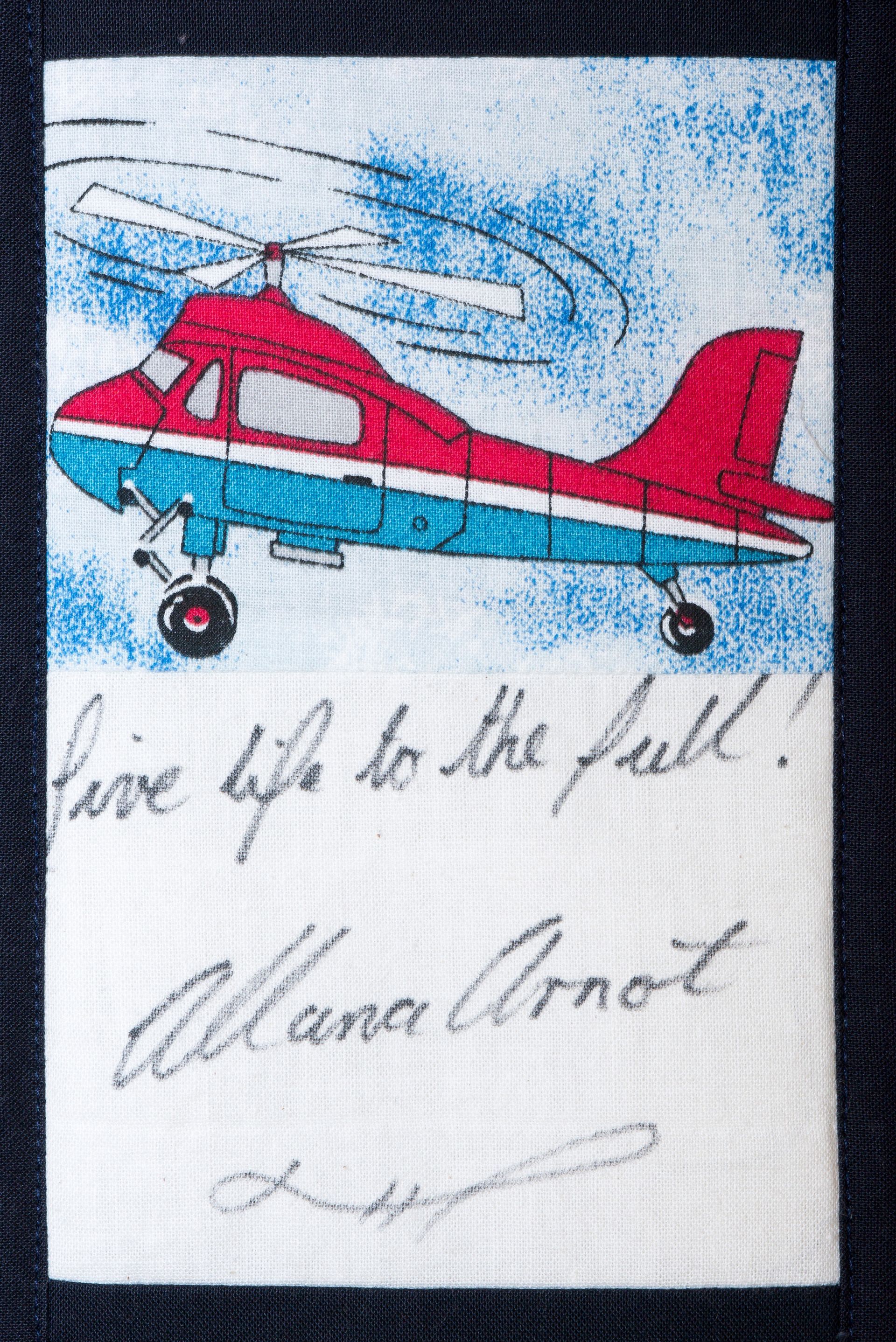 Red helicopter flying under a blue sky with handwritten text and signature below.