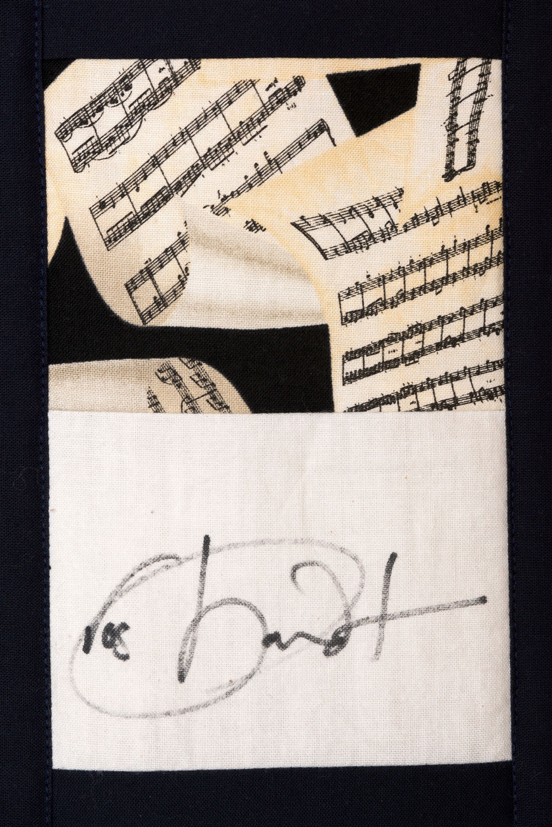 Handwritten signature on white paper with black patterned fabric above it