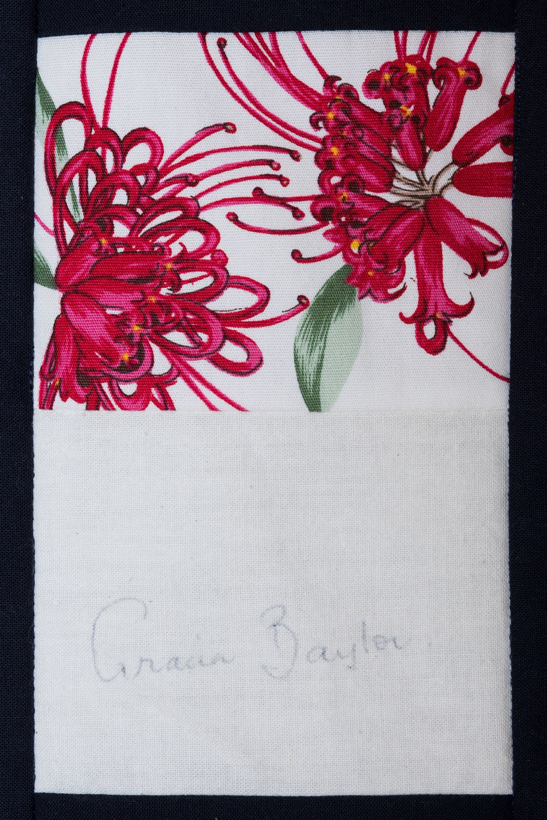 White towel with red floral embroidery and a green leaf on a dark background