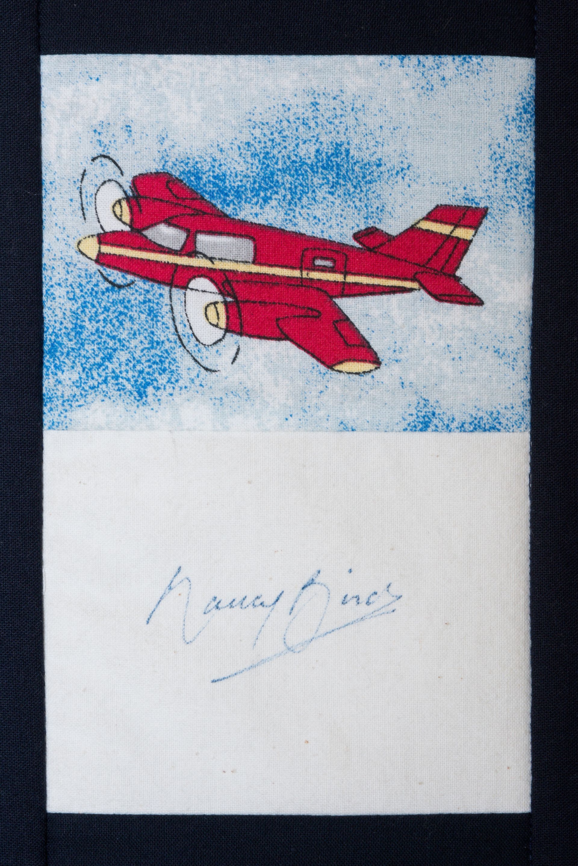 Red biplane flying against a blue sky, with faint handwritten text below.