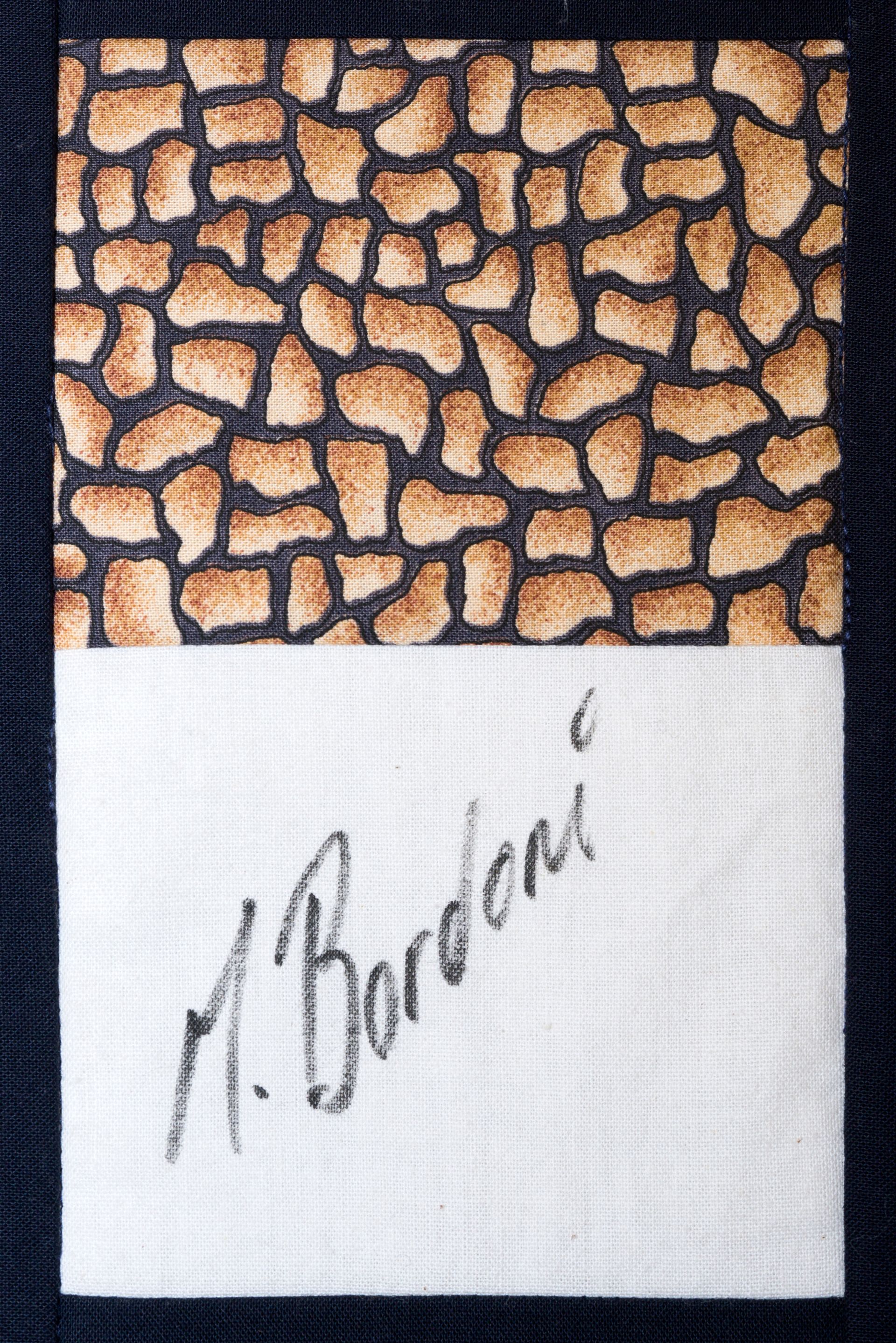 Textured fabric label with tan mosaic pattern and handwritten signature on white section