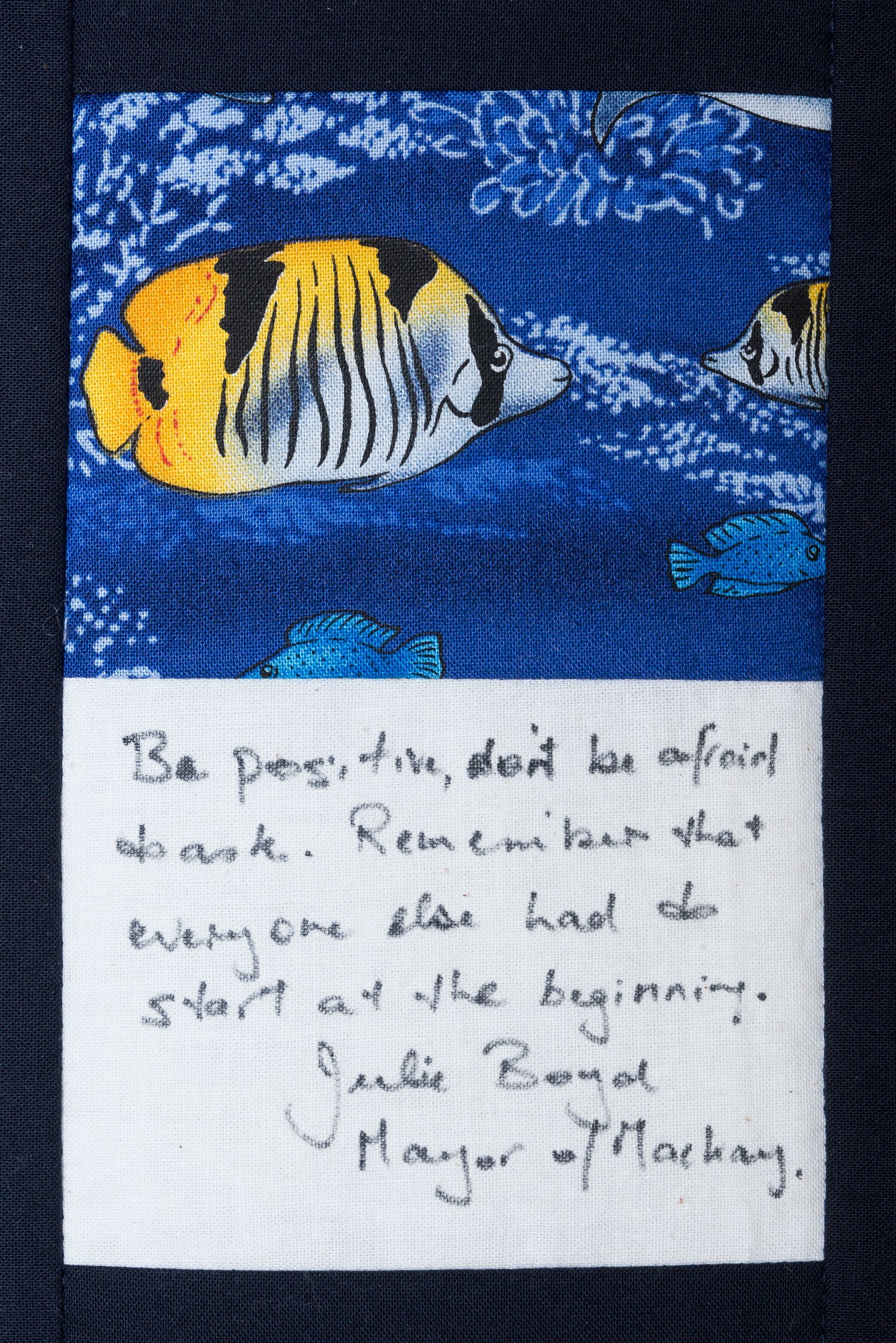 Handwritten quote on a blue fish painting with a yellow-black striped fish and smaller fish nearby.