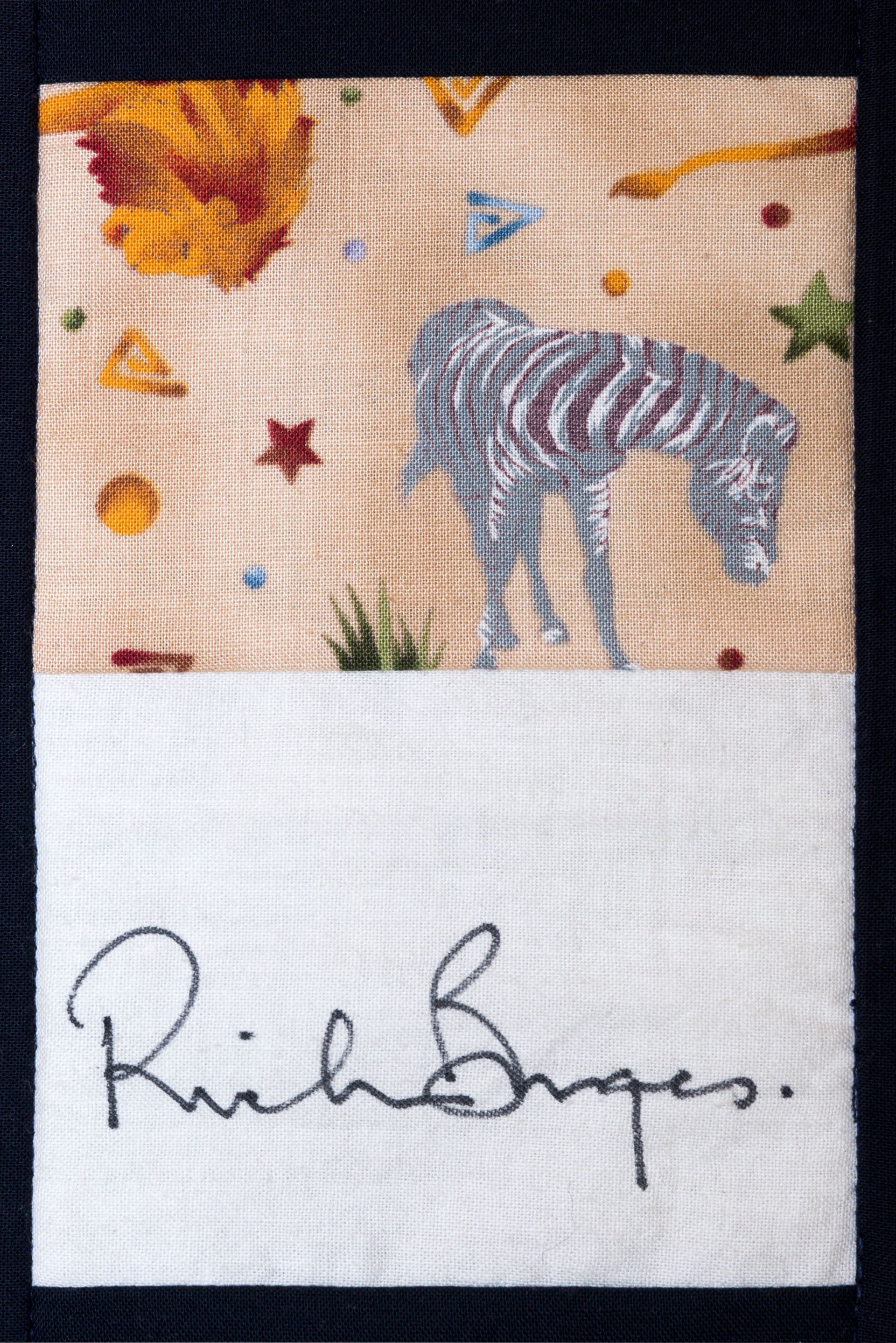 Embroidered giraffe under colorful stars with a handwritten signature below