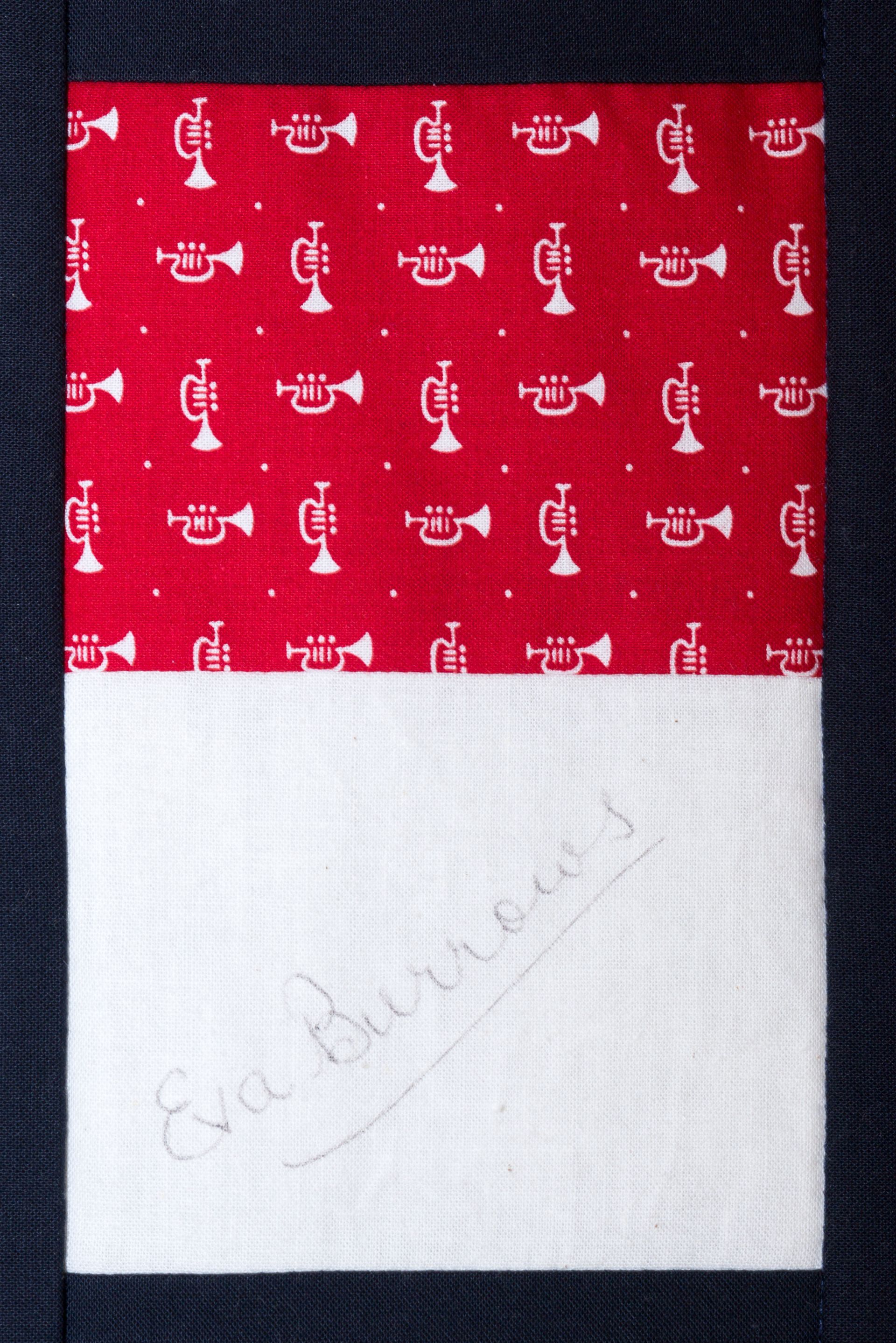 Red patterned fabric label with a white lower panel and faint embossed text.