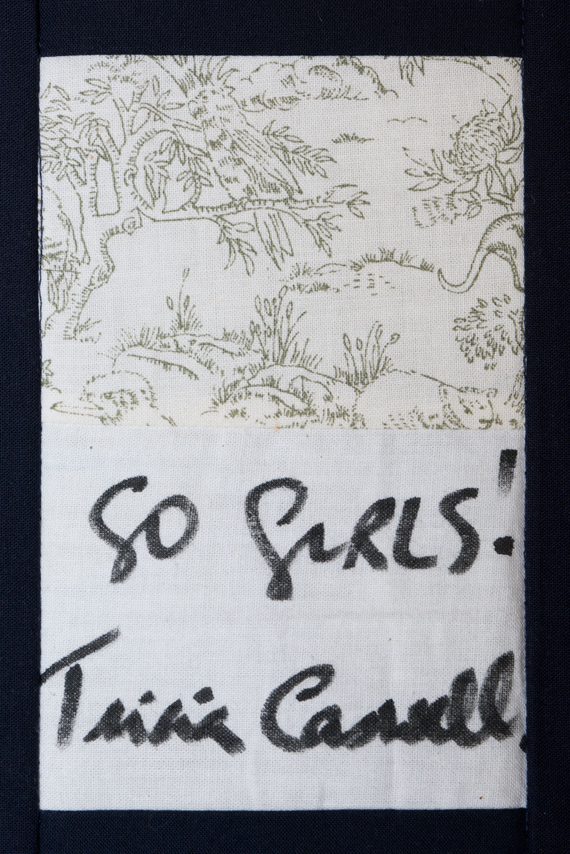 Autographed white label on dark fabric background, signed