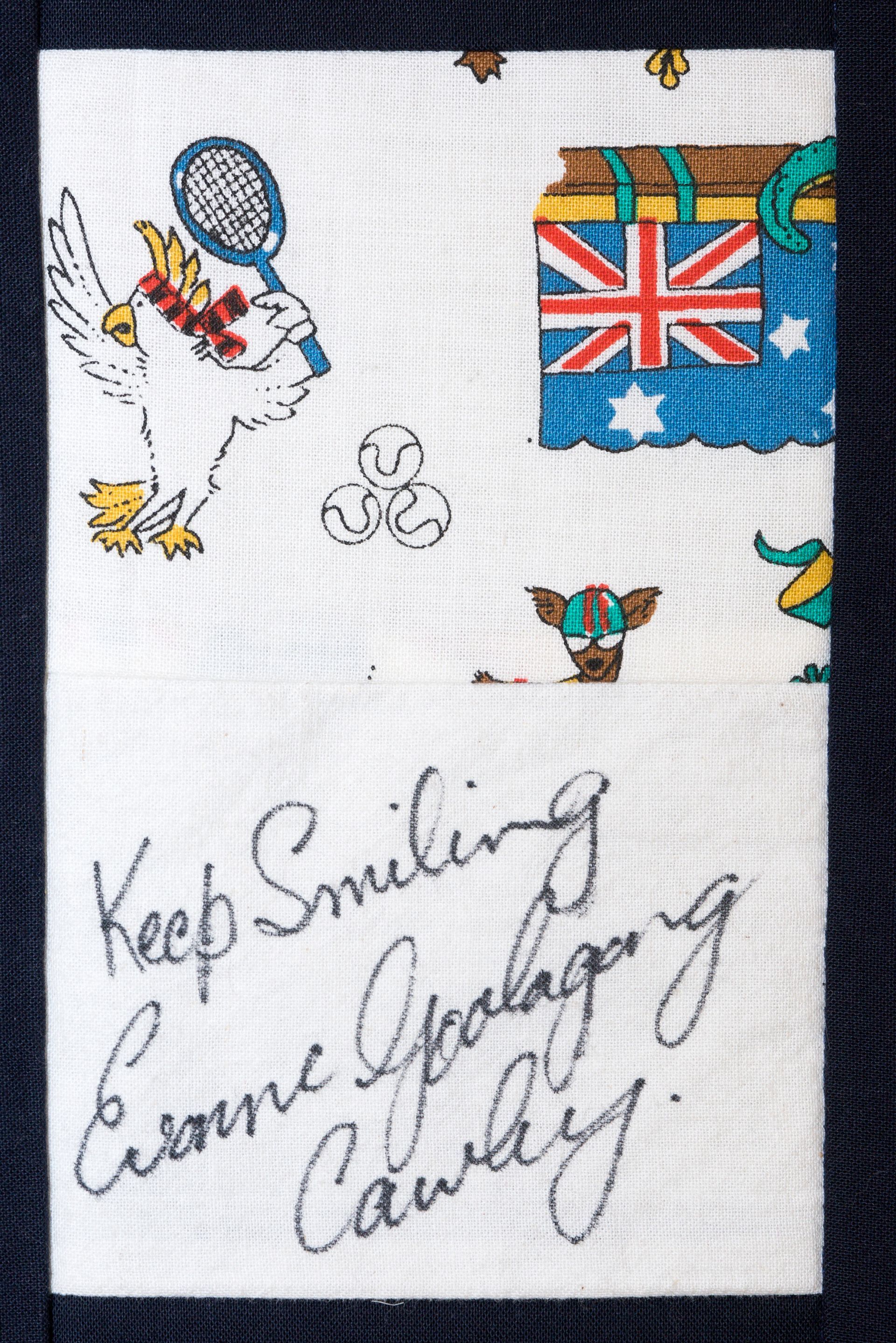 White fabric with colorful embroidered patches and handwritten text saying “Keep Smiling” and “Love, England.”