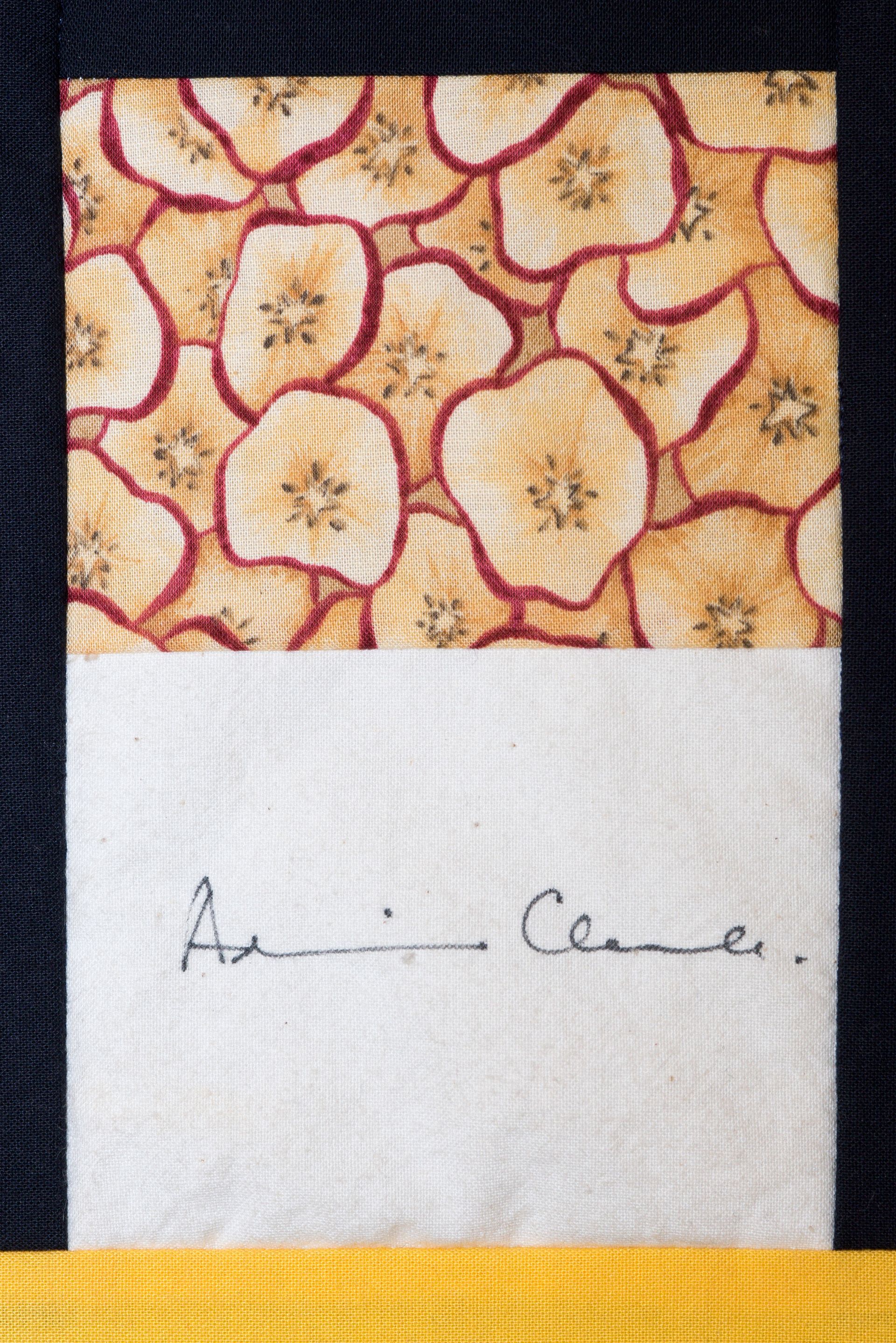 Patterned fabric label with a handwritten signature below.