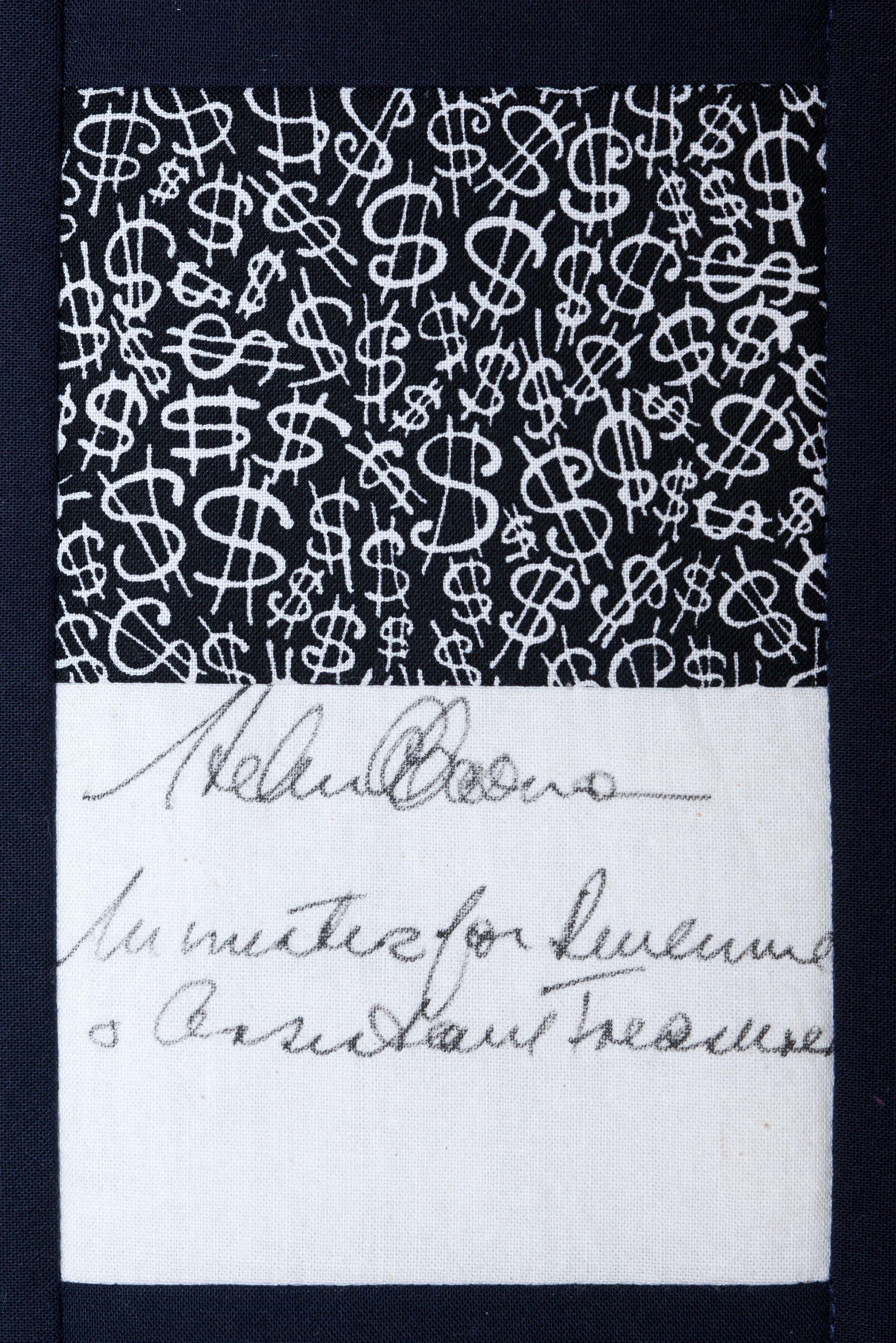 Close-up of a black patterned fabric with a white label showing handwritten notes.
