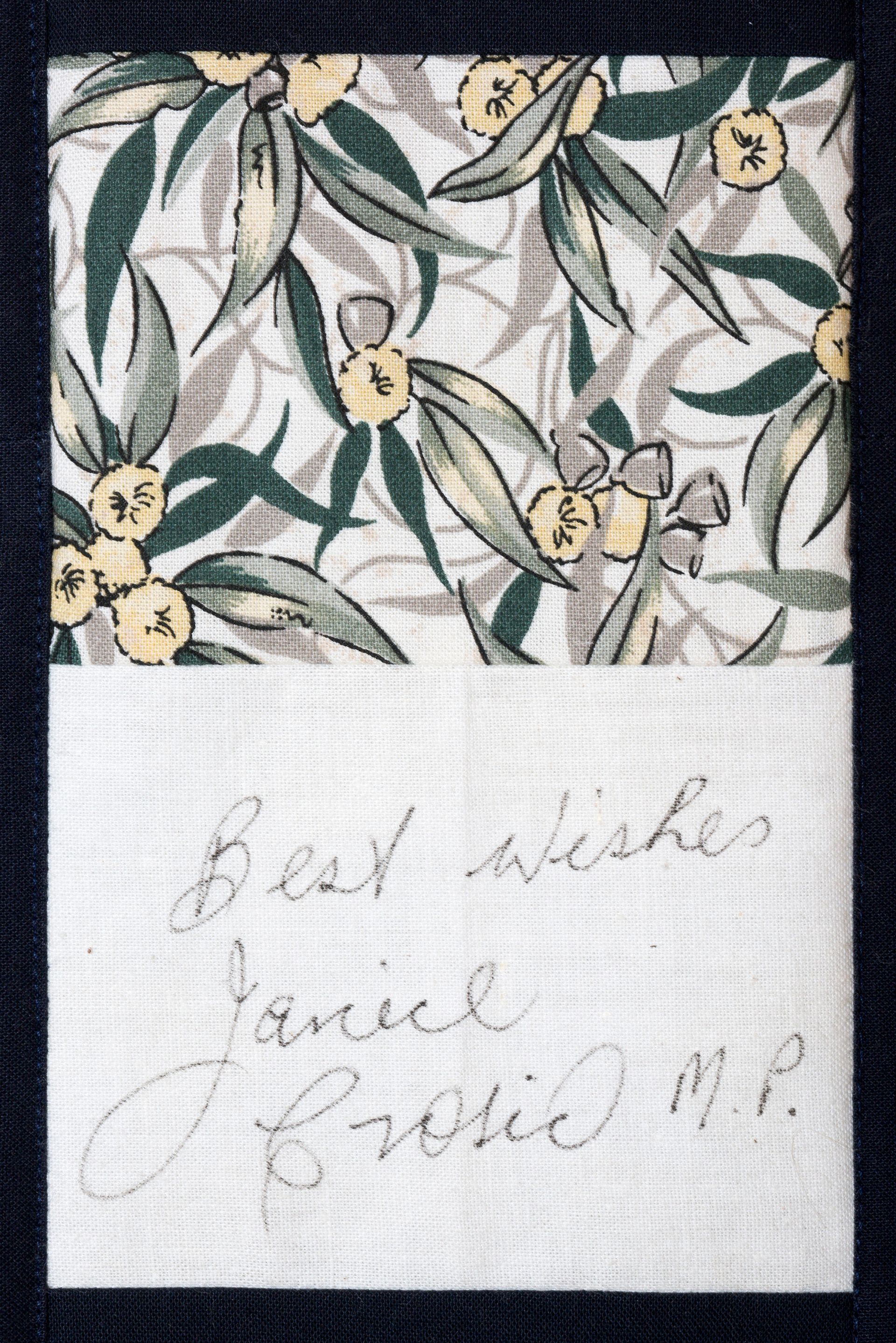 Handwritten note beneath a floral fabric swatch, reading “Best wishes” and a cursive signature.