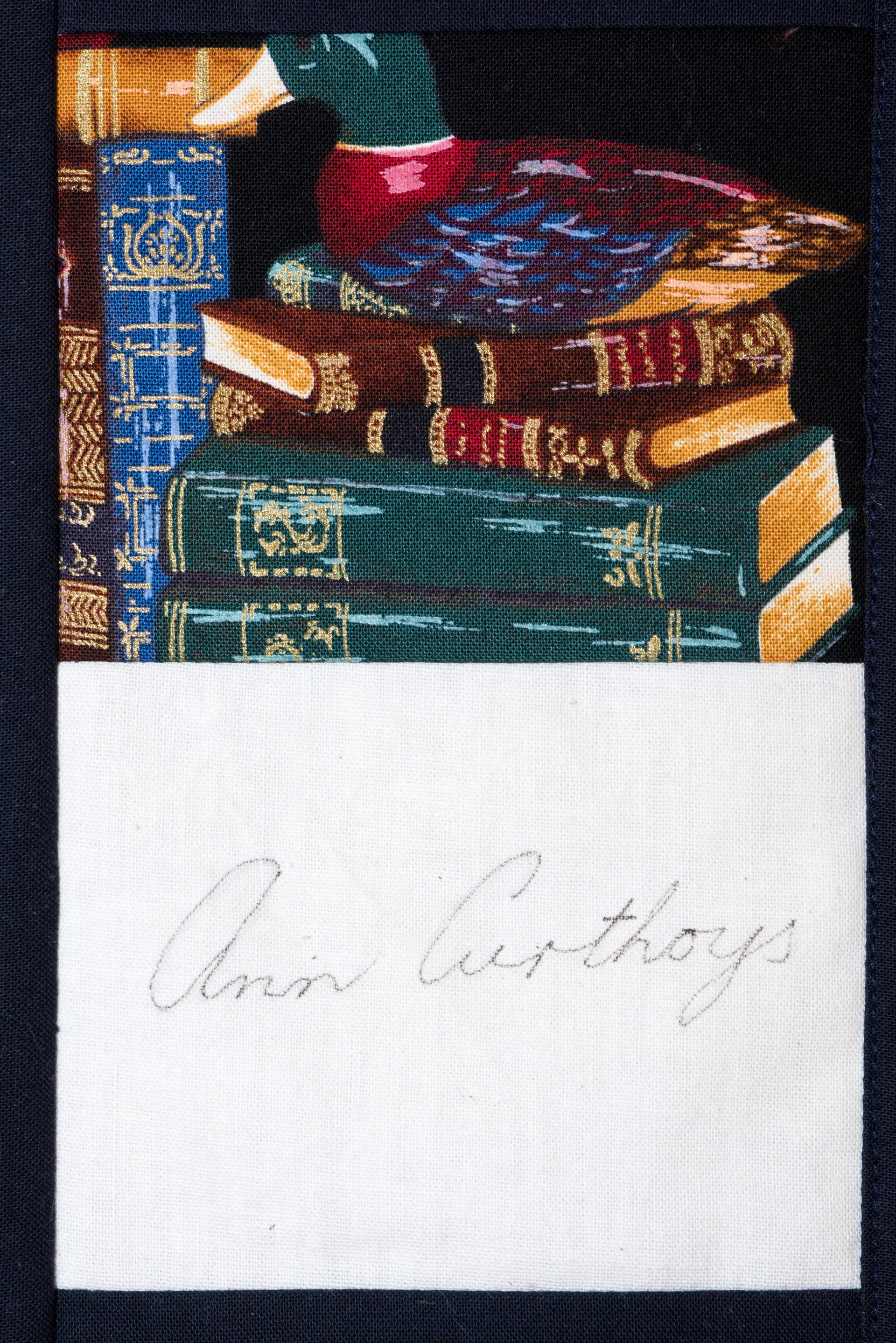 Stacked colorful books above a white page with faint handwritten signature.