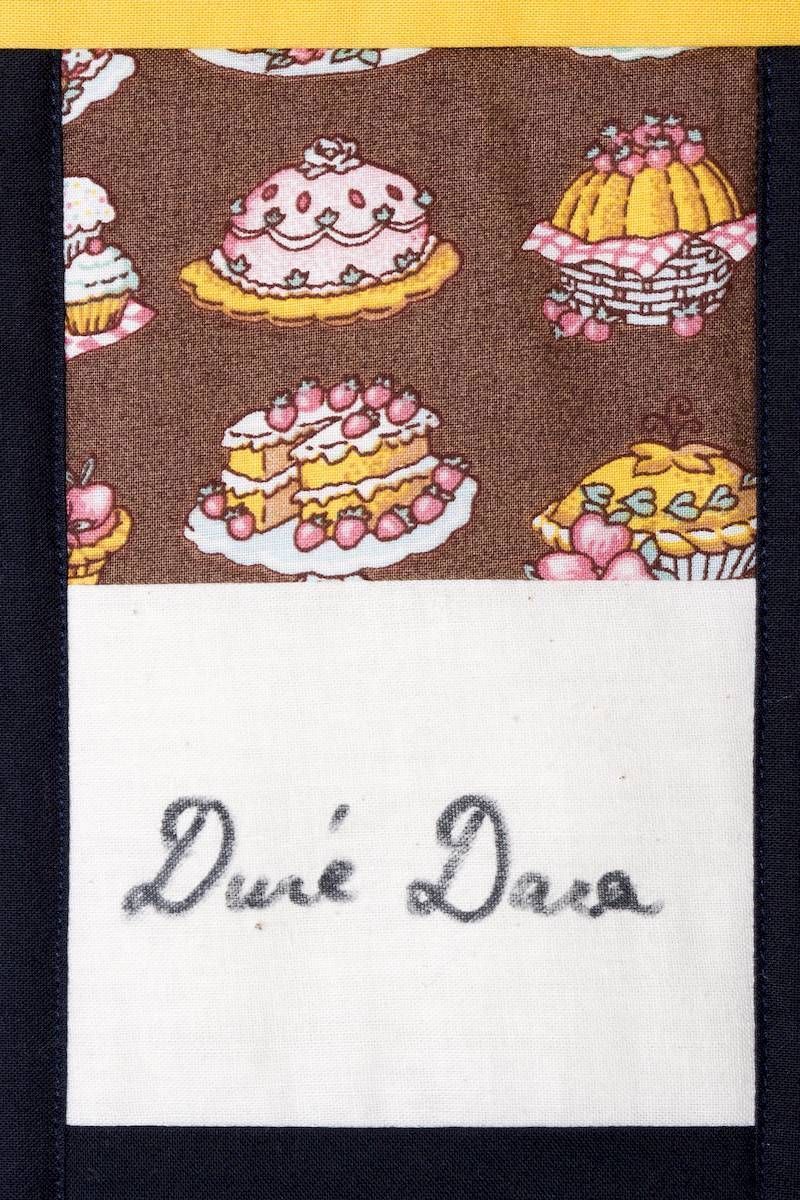 Brown dessert-patterned fabric above a white label reading “Dui Dera”