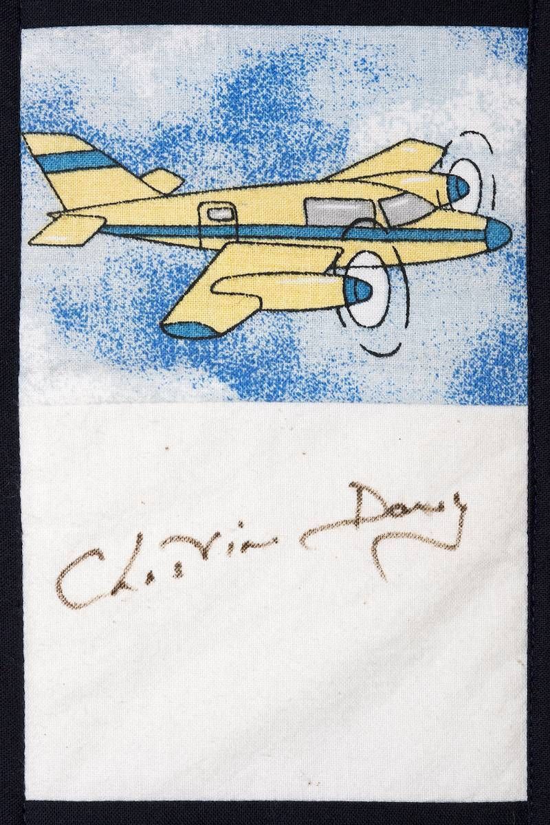 Yellow airplane drawing on blue background with a handwritten signature below