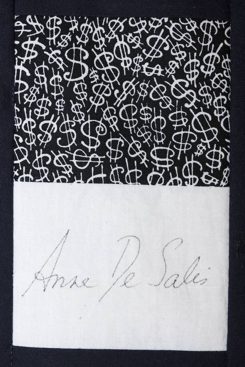 Patterned black-and-white fabric with a handwritten signature on a white panel below
