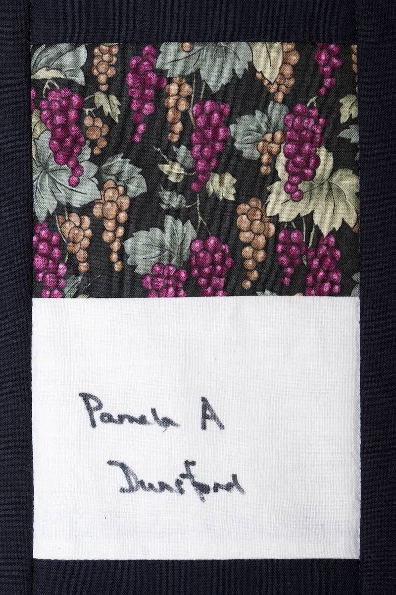 Handwritten label on a dark floral fabric swatch reading “Panda A Thanjavur.”