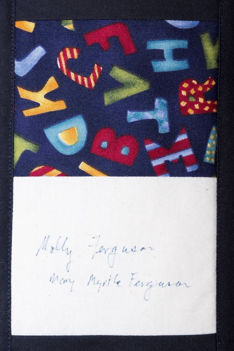 Colorful letter-pattern fabric above a white note with faint handwritten text
