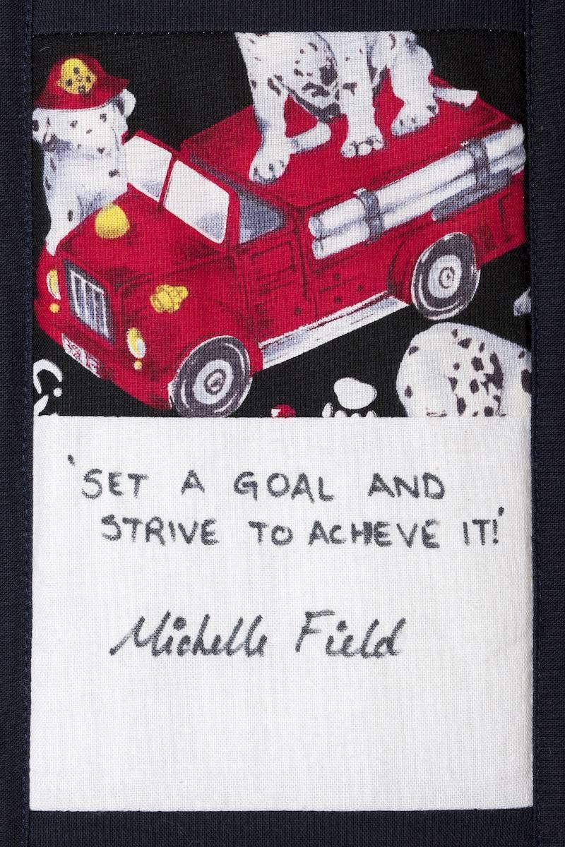 Red toy truck carrying a white dog, with a note reading, “Set a goal and strive to achieve it!”