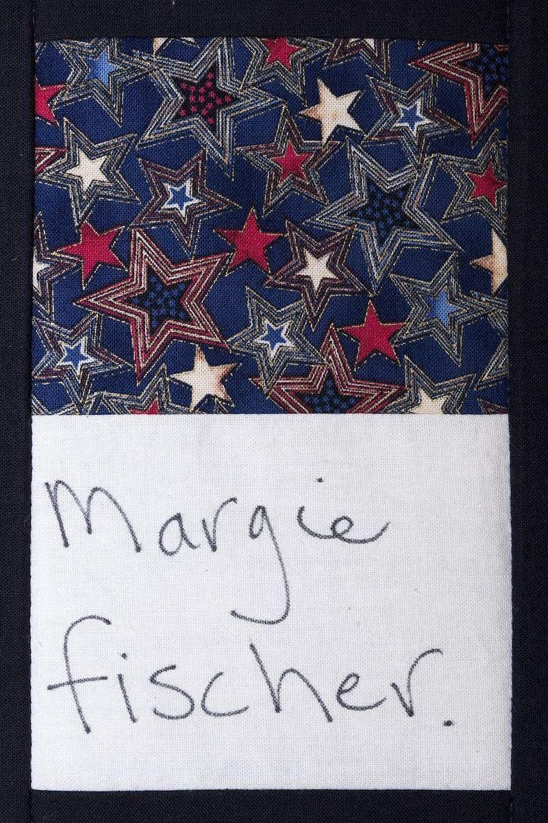 Fabric with red, white, and blue stars above a handwritten note reading “Margie fischer.”