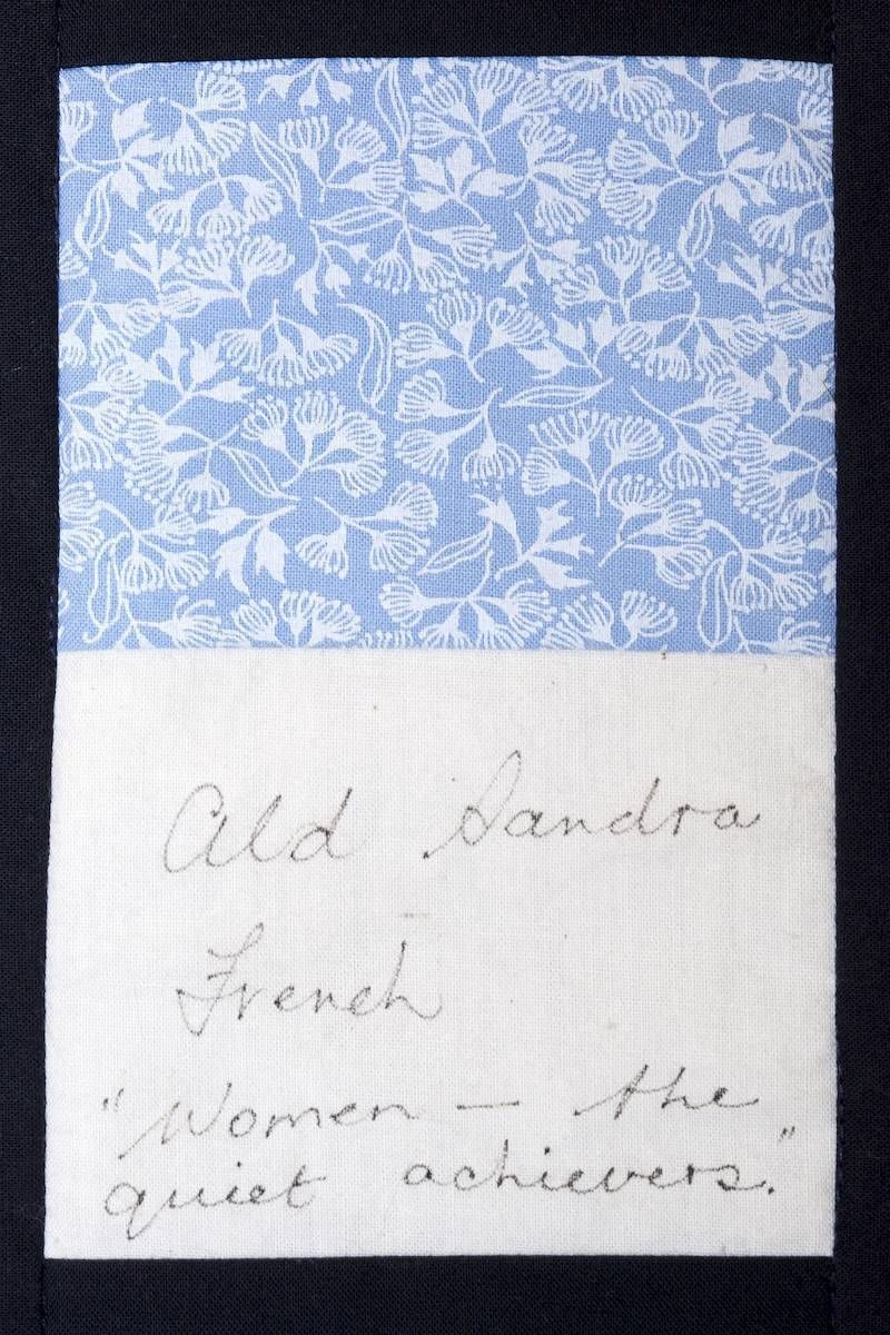 Blue floral fabric swatch above handwritten note on white paper.