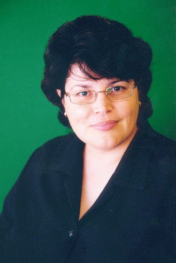 Portrait of a person with glasses and dark hair against a green background