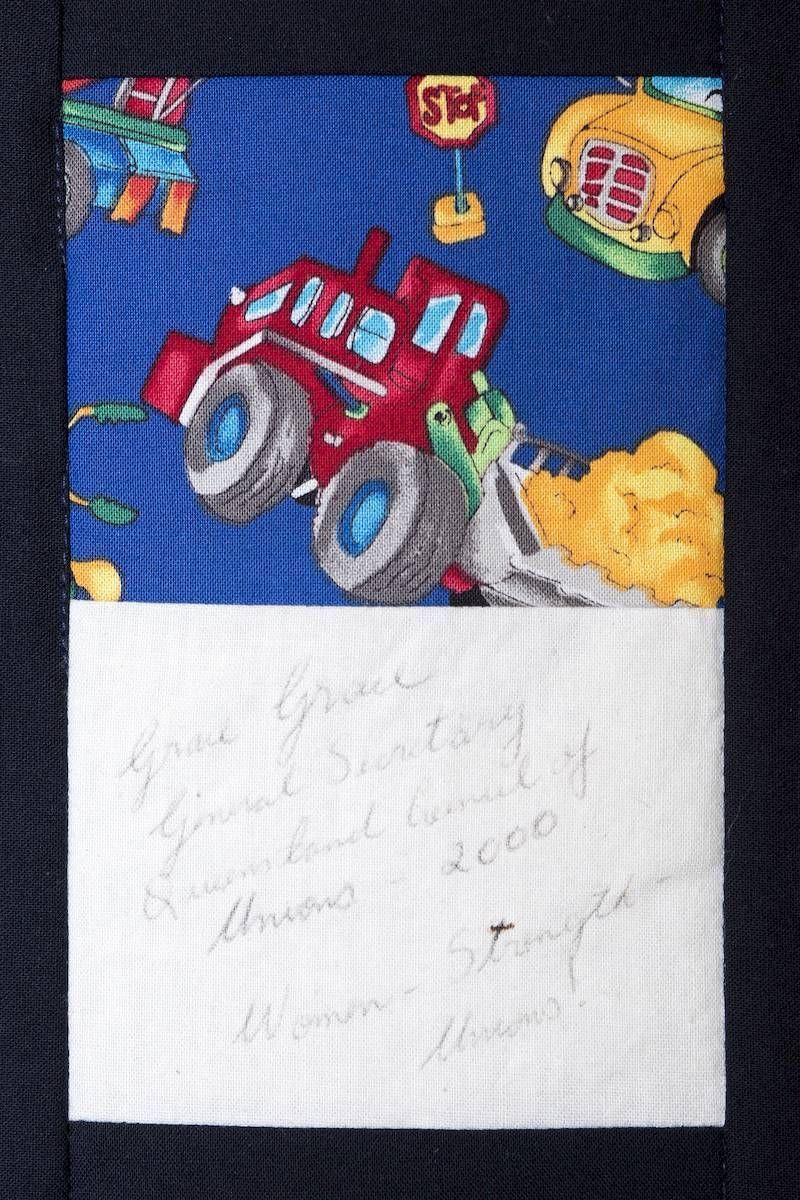 Red toy tractor on blue patterned fabric beside a torn white paper note