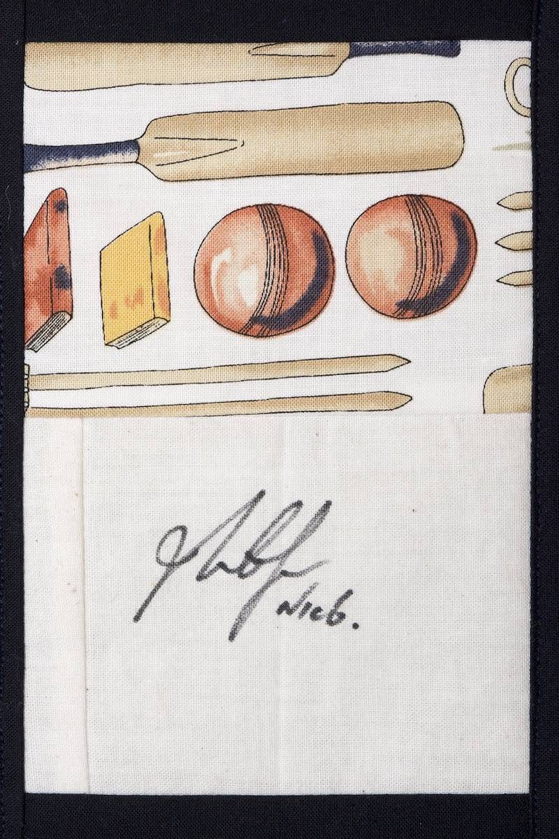 Assorted wooden and round objects on white fabric, with a handwritten signature below