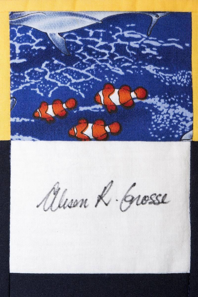 Clownfish in blue coral scene above an autograph on white fabric