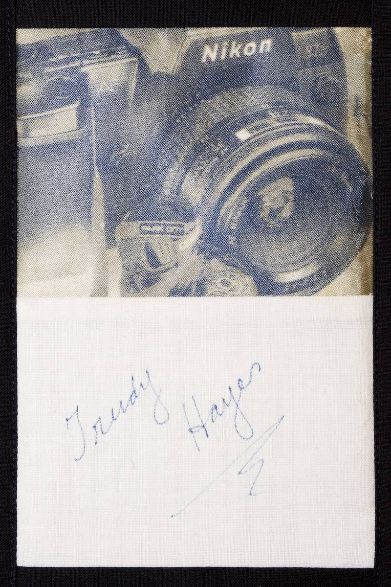 Blue woven fabric above a white note with faint handwritten signature