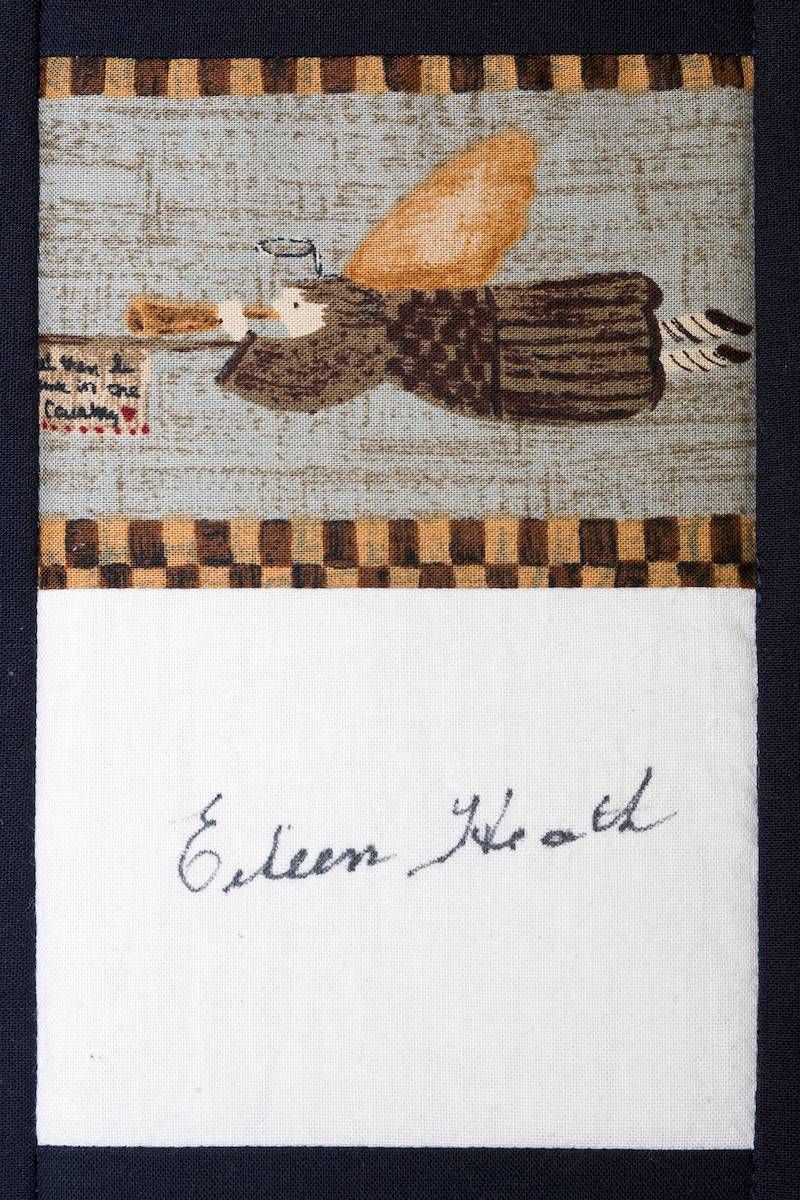 Small woven artwork showing a loaf and knife above a white label with handwritten “Edeen Black.”