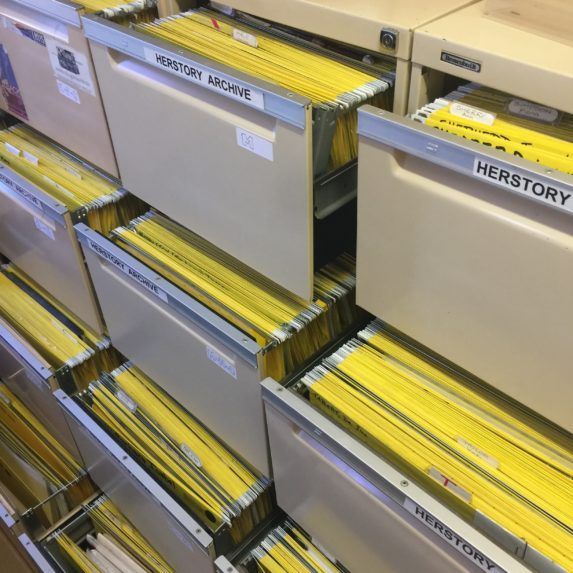 Rows of beige filing cabinets with yellow folders in a library or archive storage area