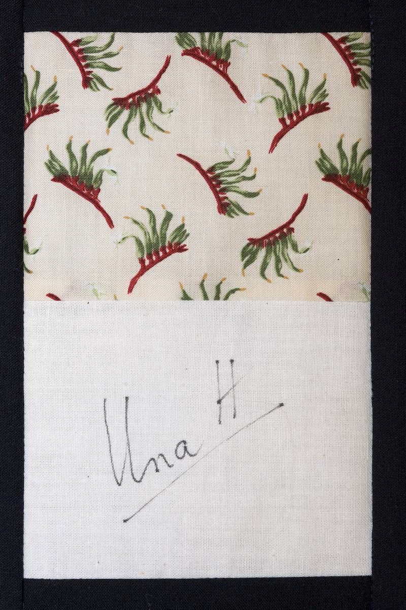 Patterned fabric swatch with red and green sprigs above a handwritten note on white paper.
