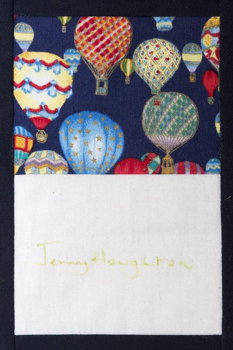 Hot air balloons on a dark sky above a white card with faint yellow handwritten text