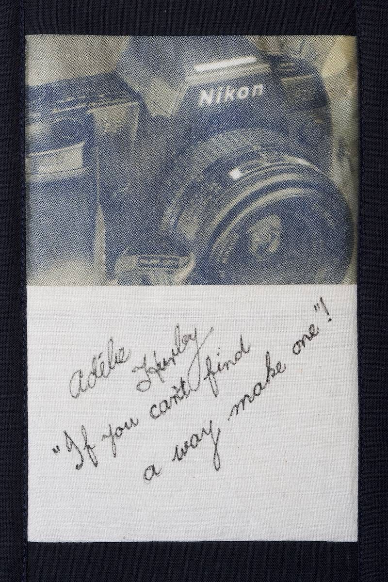 A camera atop a handwritten note on a blue fabric background