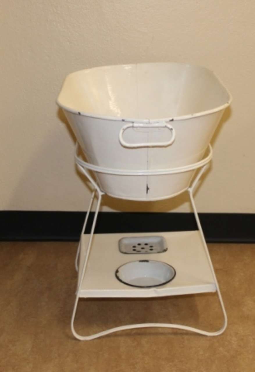 White bucket-style device on a metal stand over a floor outlet in a room corner
