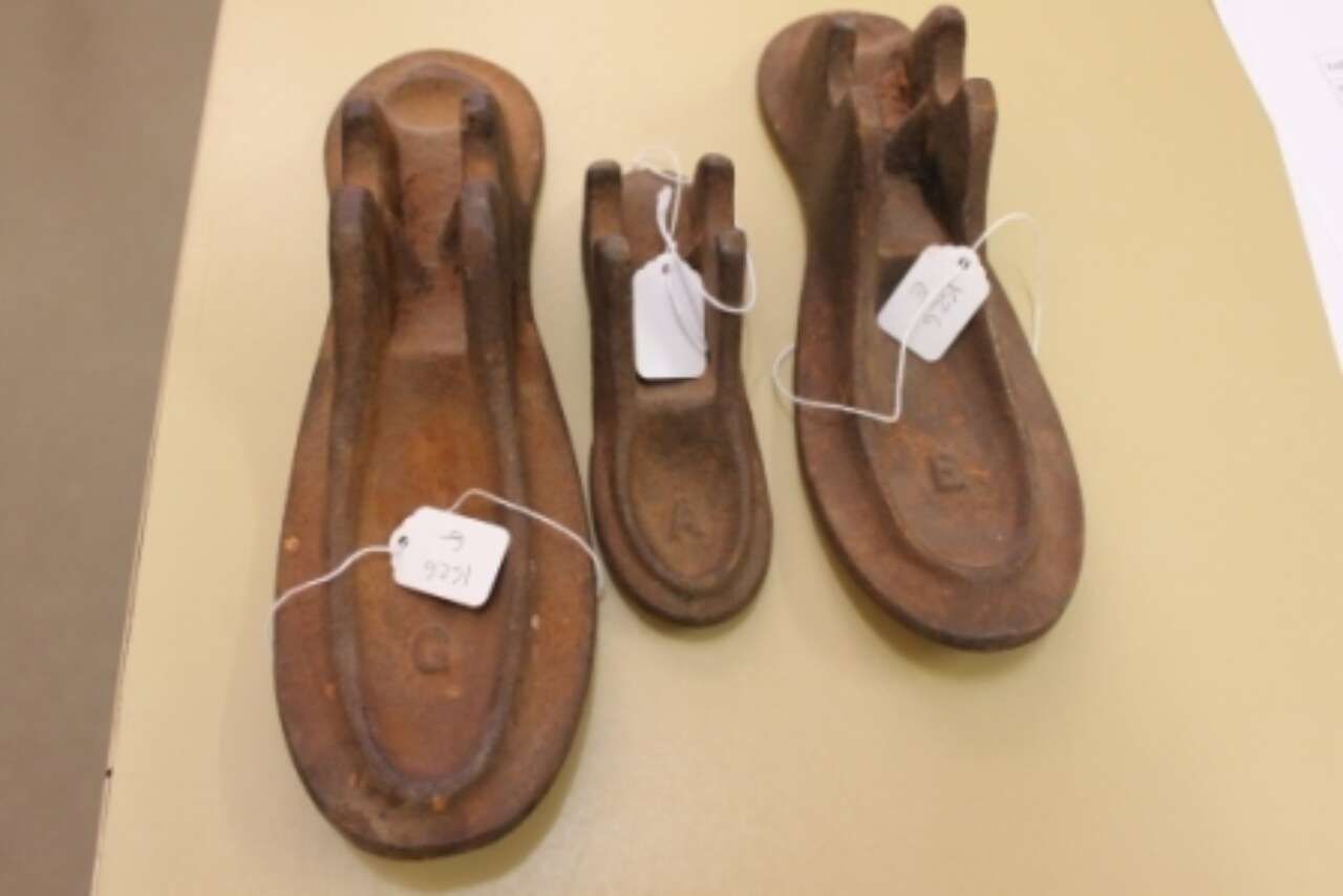 Three brown leather sandals on a beige surface, each with a white tag attached.