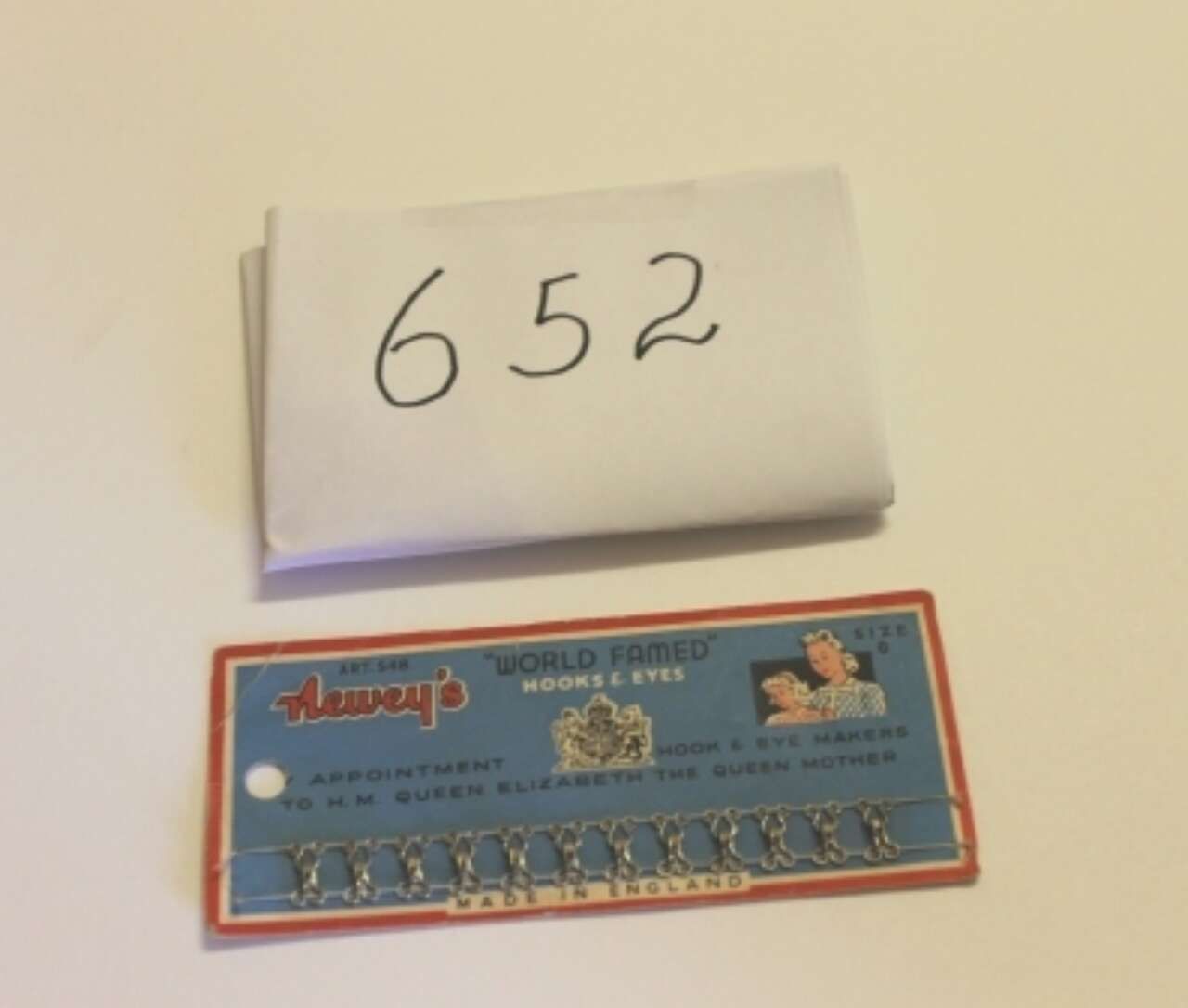 White folded note labeled “652” above a blue-and-orange pack on a beige surface.