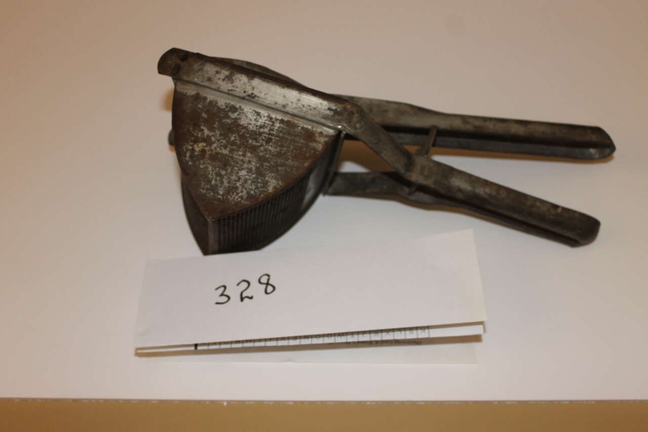 Old metal hand tool with two handles, shown above a handwritten “328” label and a thin rod on white background