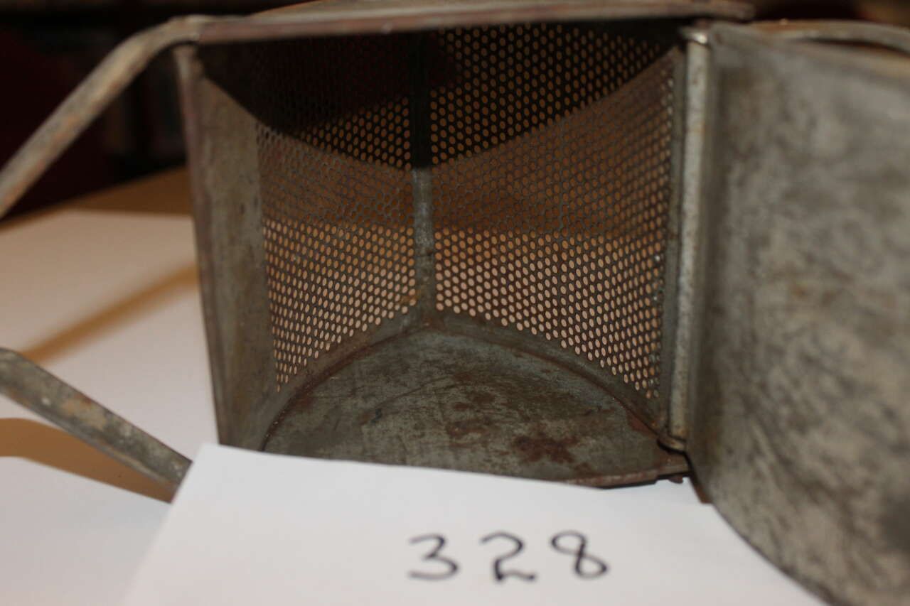 Close-up of a metal mesh cylindrical container labeled 328 on a white card