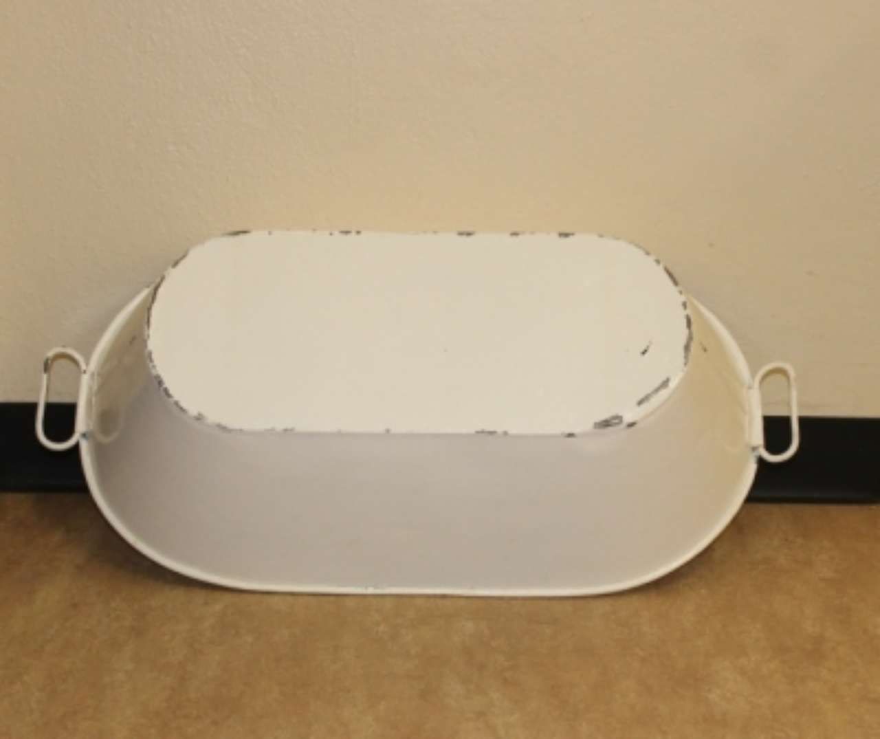White plastic step stool with side handles against a beige wall and floor.