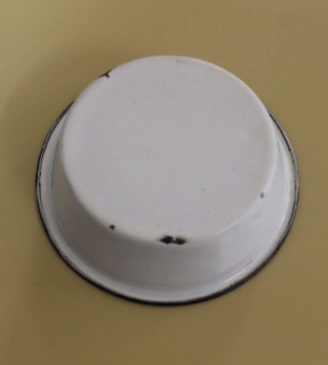 White round plastic cap or button on a beige surface with a small dark mark near the edge