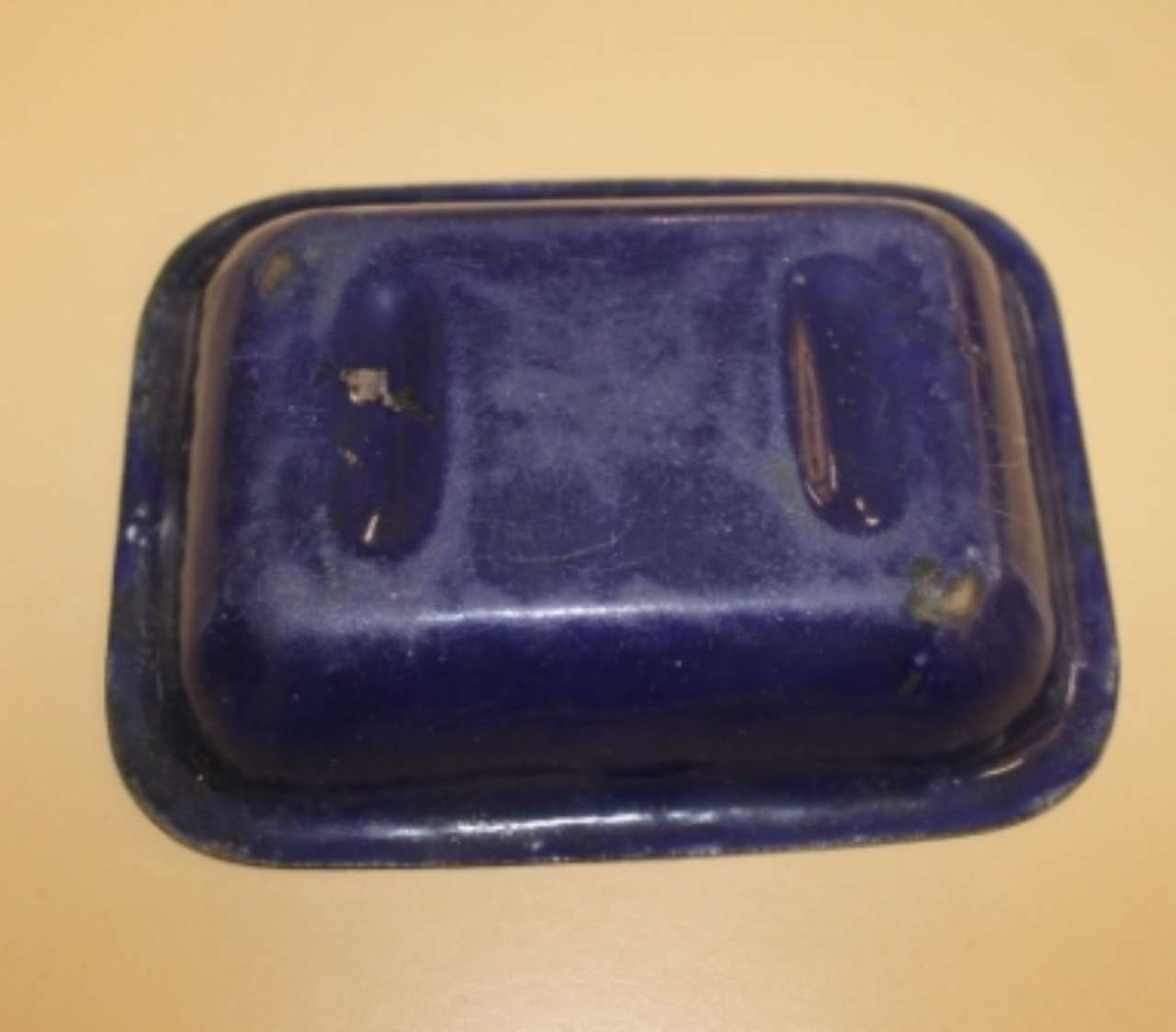 Blue glazed ceramic dish with two raised handles on a light background