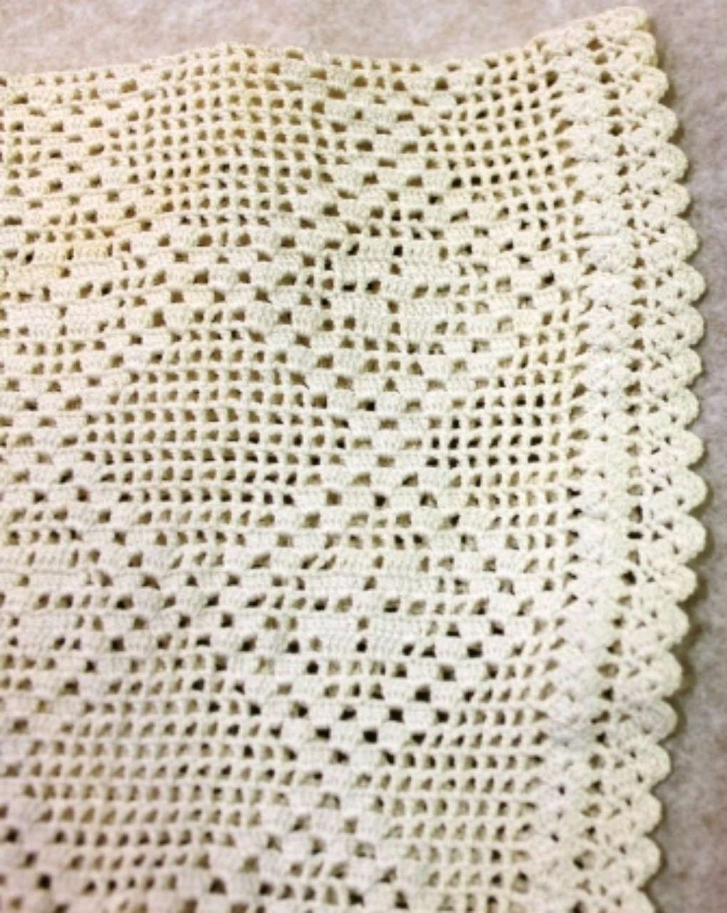 White crocheted lace fabric with scalloped edge and small openwork pattern.