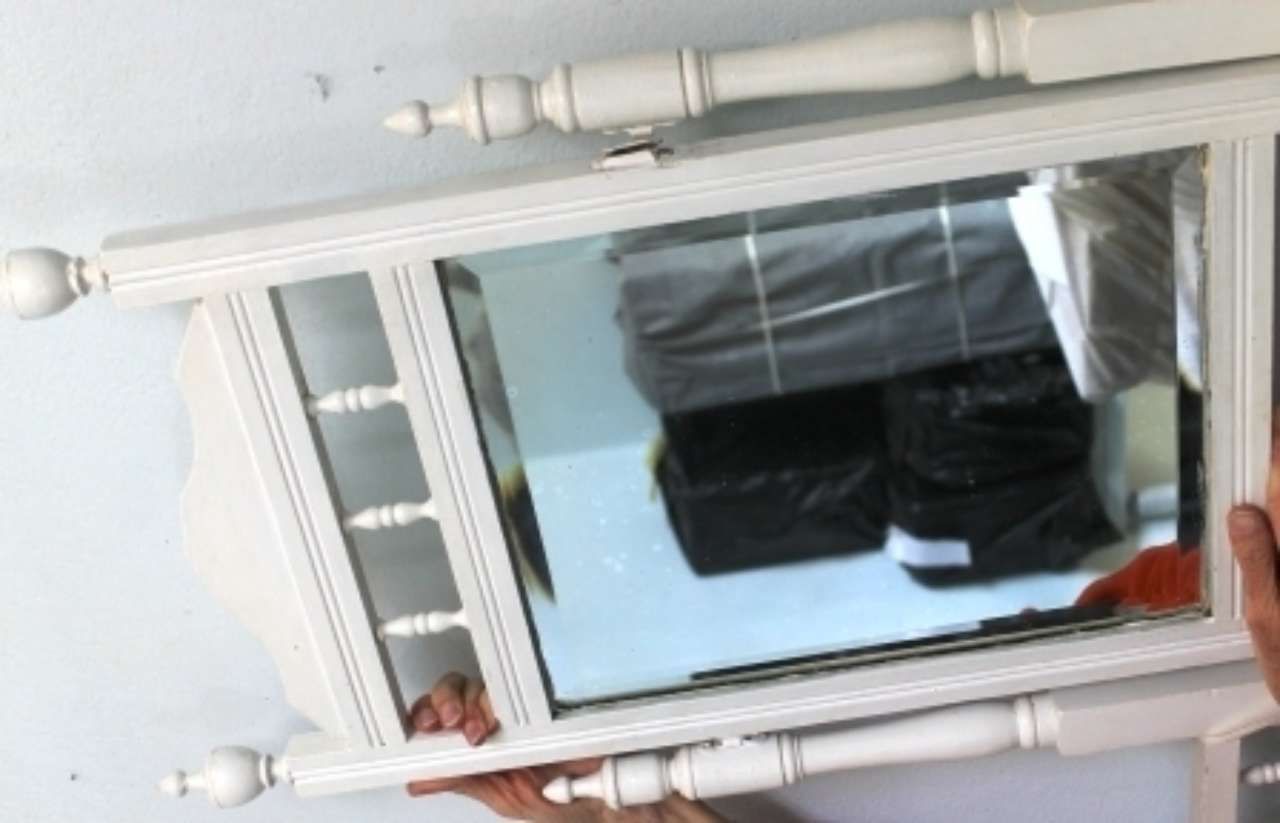 Upside-down mirror reflecting a black handbag and a hand holding the frame