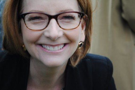 Smiling person wearing glasses and a dark jacket, close-up portrait outdoors