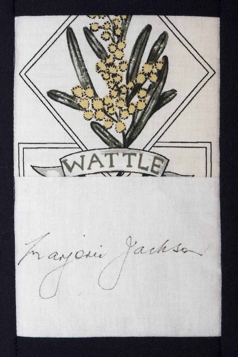 Illustrated wattle label with yellow flowers and a handwritten signature below