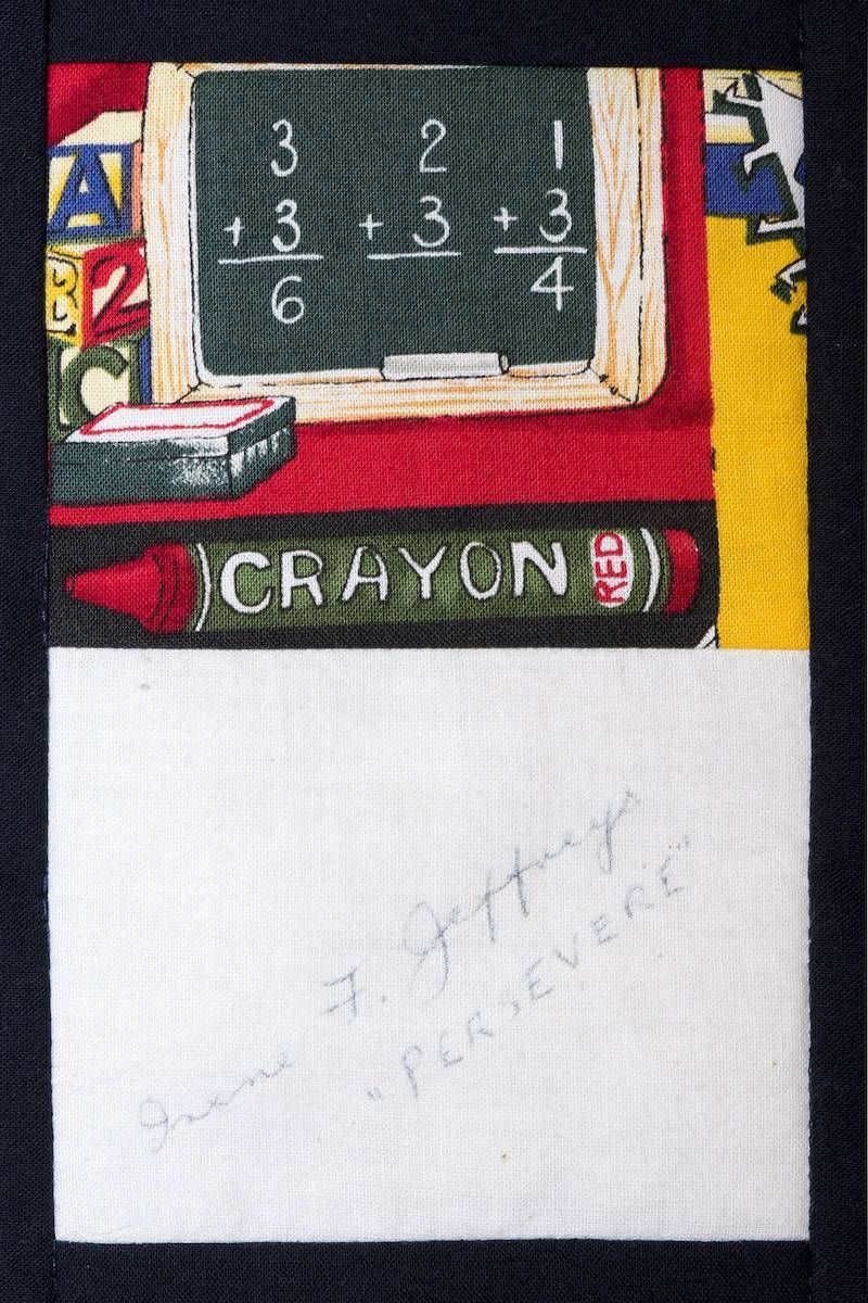 A red crayon beside a small chalkboard with chalk arithmetic and a blank white note card below.