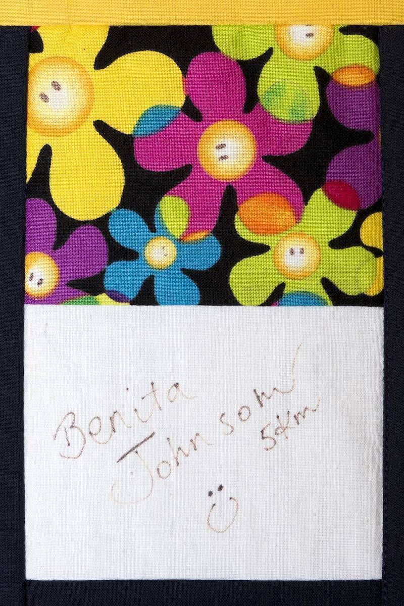 Colorful floral fabric above a white note with faint handwritten text.