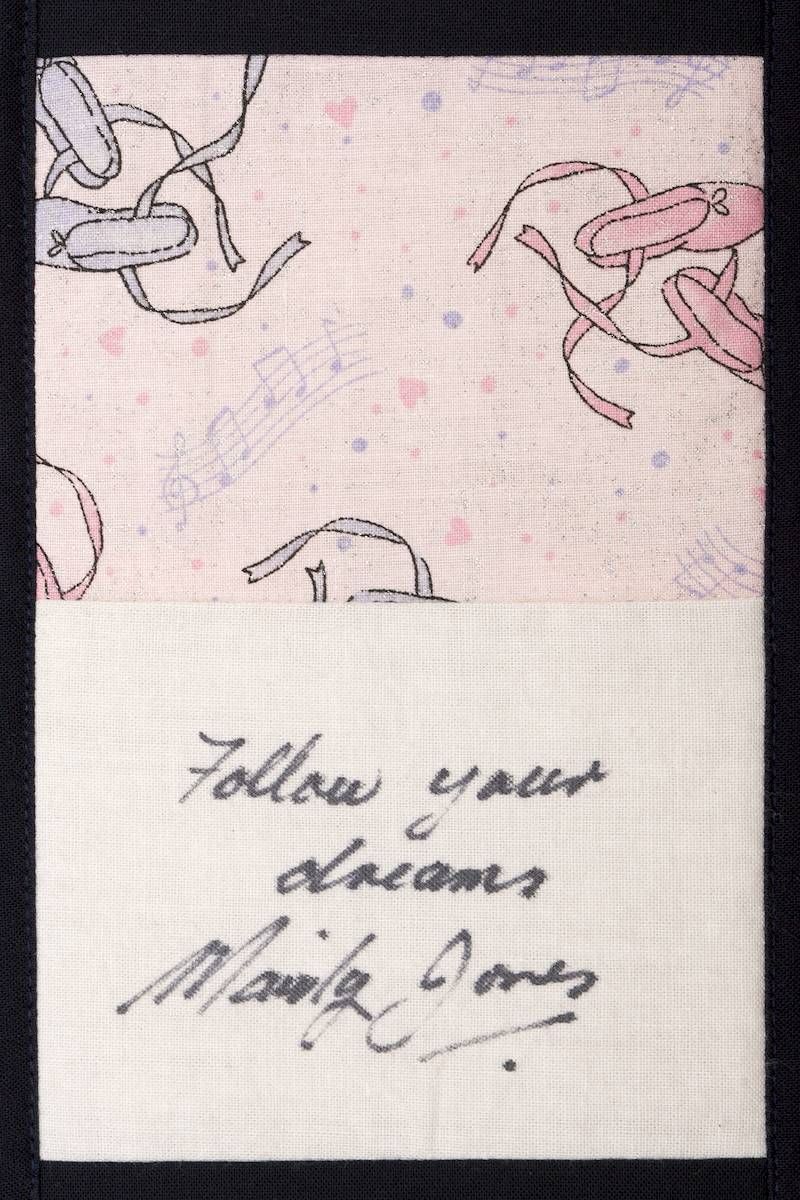 Handwritten note on patterned paper with the words “Follow your dreams” and a signature.