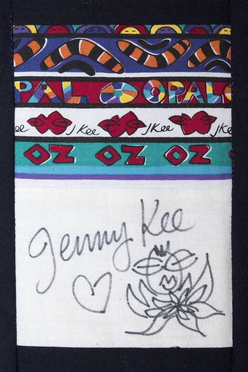 Colorful fabric panel with “OZ” designs and a white square signed “Jenny Lee” with a heart and flower doodle