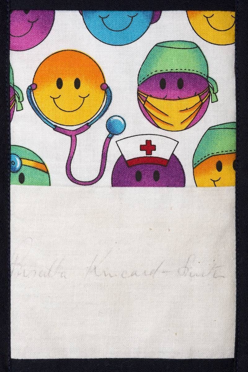 Colorful smiling face pattern on white fabric, including a nurse cap with a red cross.